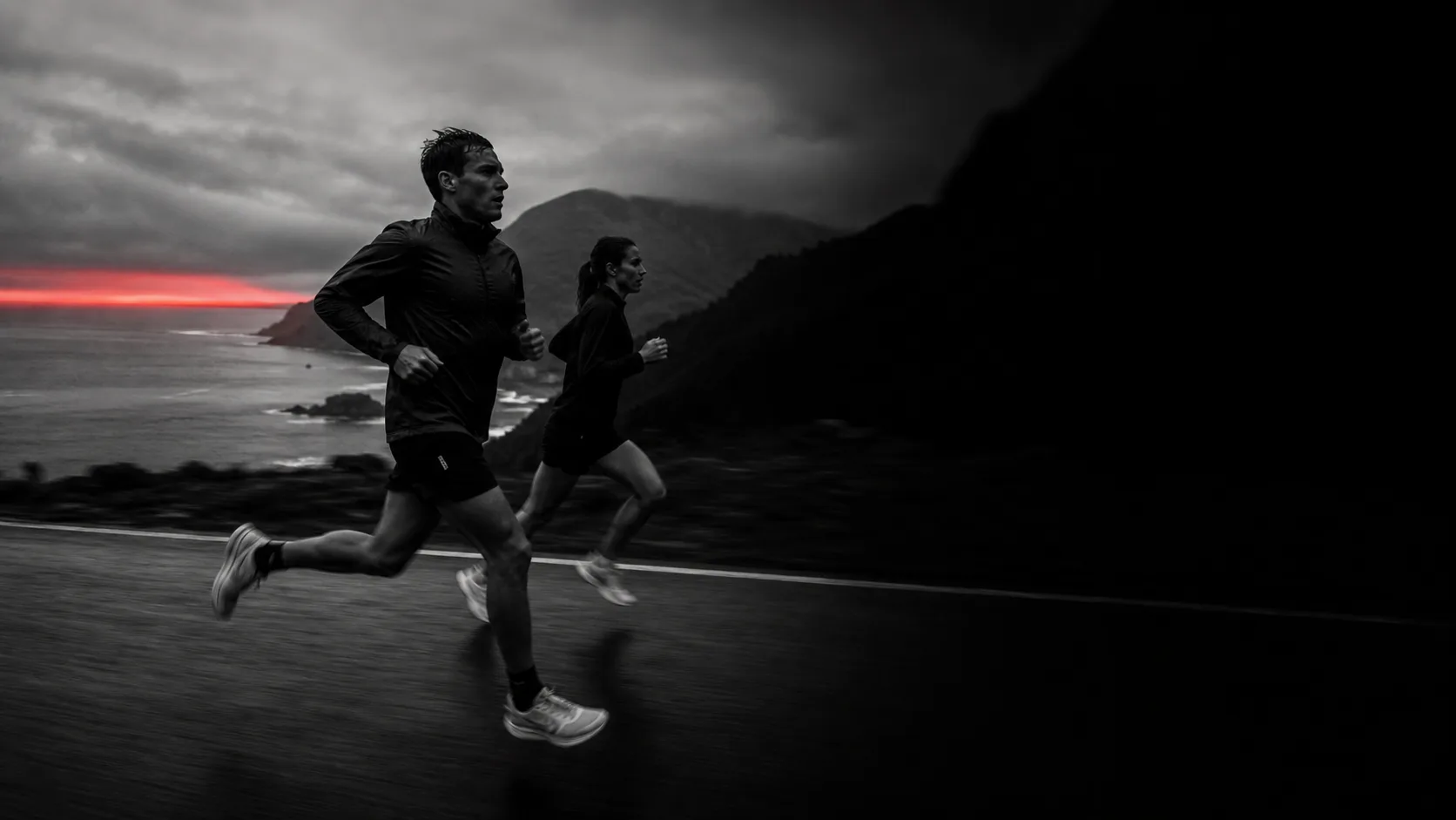 Two endurance runners training on a coastal road